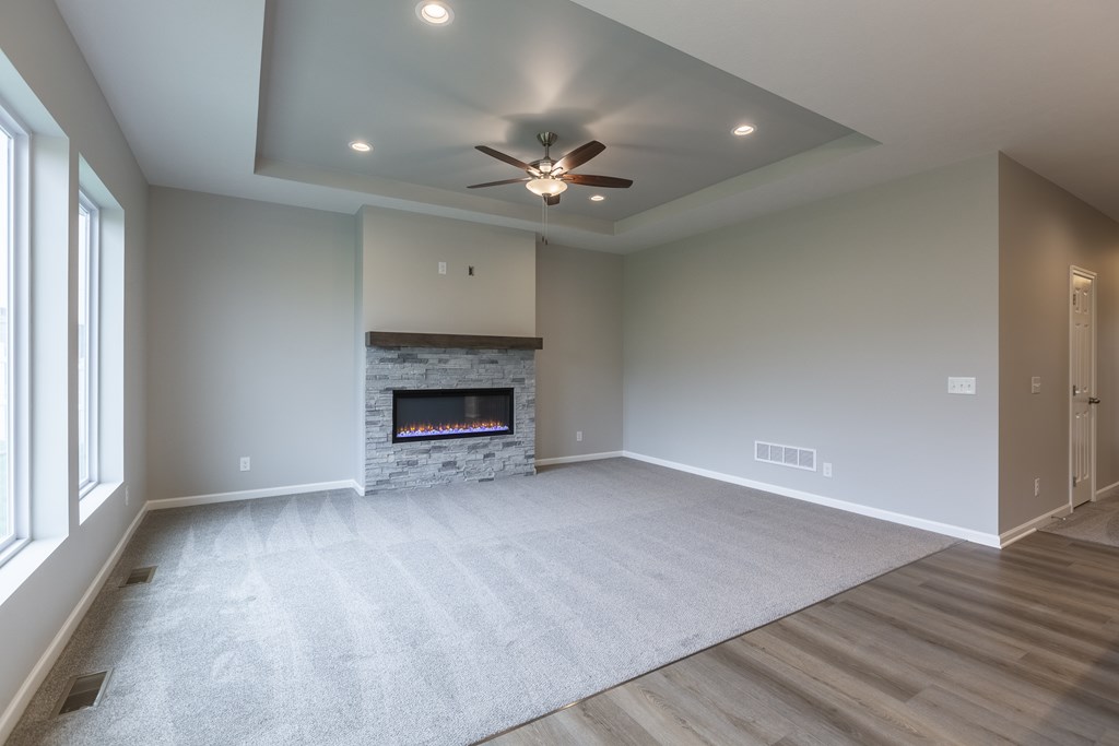 A spacious living room with a fireplace and a ceiling fan.