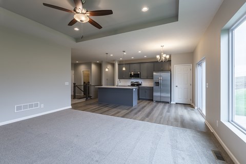 A spacious kitchen and living room with a ceiling fan and recessed lighting.