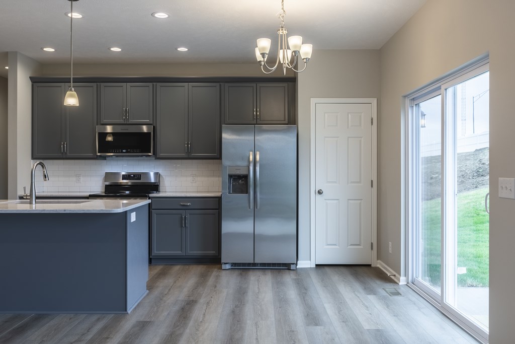 A kitchen with a refrigerator, sink, and cabinets.