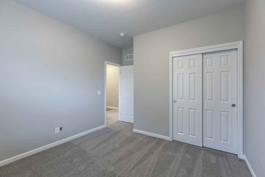 A room with a carpeted floor and a white door.