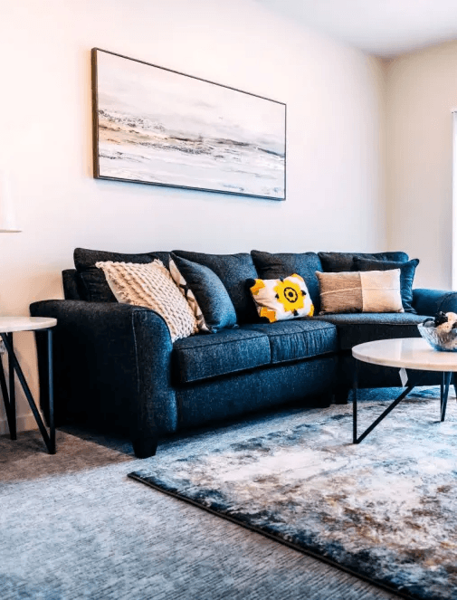 A living room with a dark blue couch and a white table.