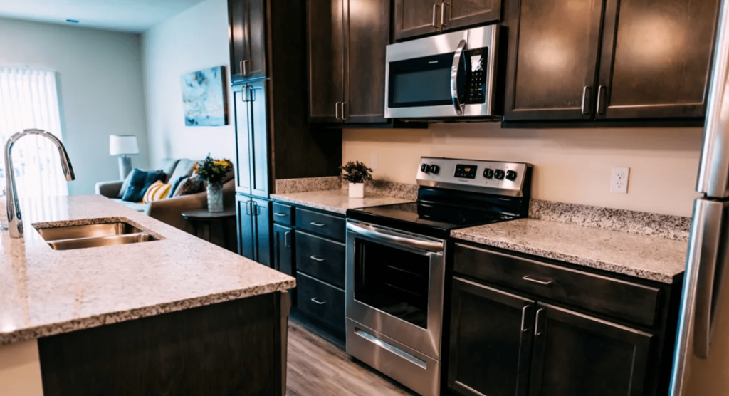 A modern kitchen with dark wood cabinets and stainless steel appliances.