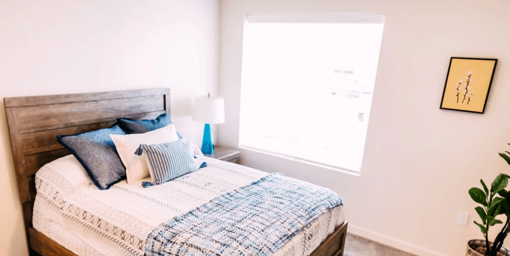 A bed with a white comforter and a blue and white checkered blanket.