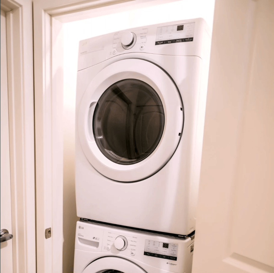 A white washing machine is stacked on top of another white washing machine.