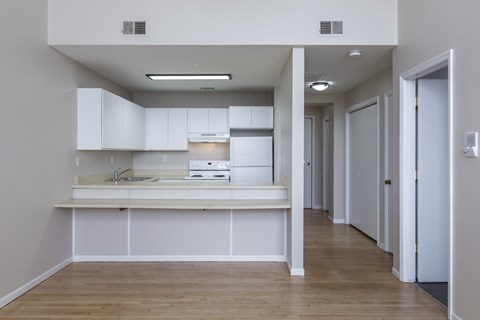 A kitchen with white cabinets and a wooden floor.