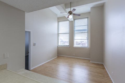 A room with a ceiling fan and two windows.
