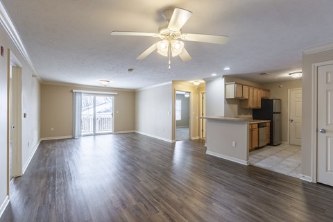 A spacious living room with a ceiling fan and sliding glass doors.