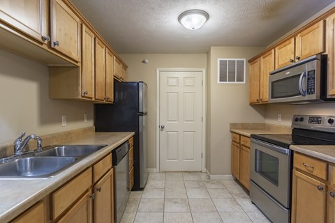 A kitchen with wooden cabinets and a black refrigerator.