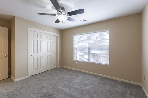 A room with a ceiling fan and a window with blinds.
