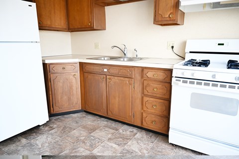 A kitchen with wooden cabinets and a white stove.
