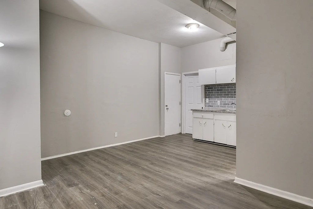 A kitchen area with white cabinets and a grey floor.