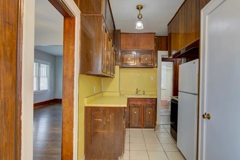 A kitchen with wooden cabinets and a yellow wall.