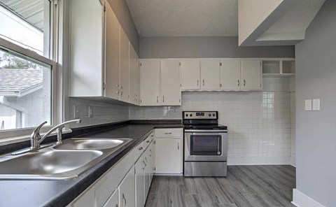 A modern kitchen with a stainless steel sink and white cabinets.
