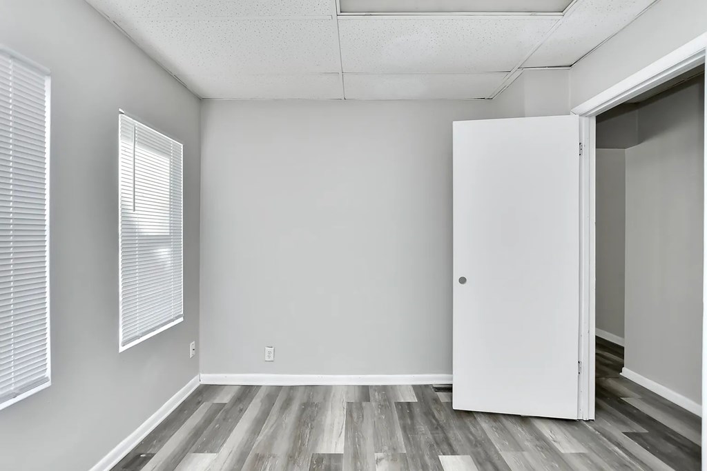 A room with a white door and a window with blinds.