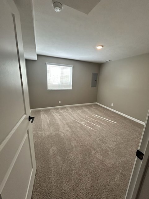A room with a carpeted floor and a window with blinds.