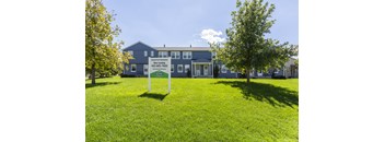 Exterior view of a multi building apartment community with green lawn and sidewalks at Colonial Park.