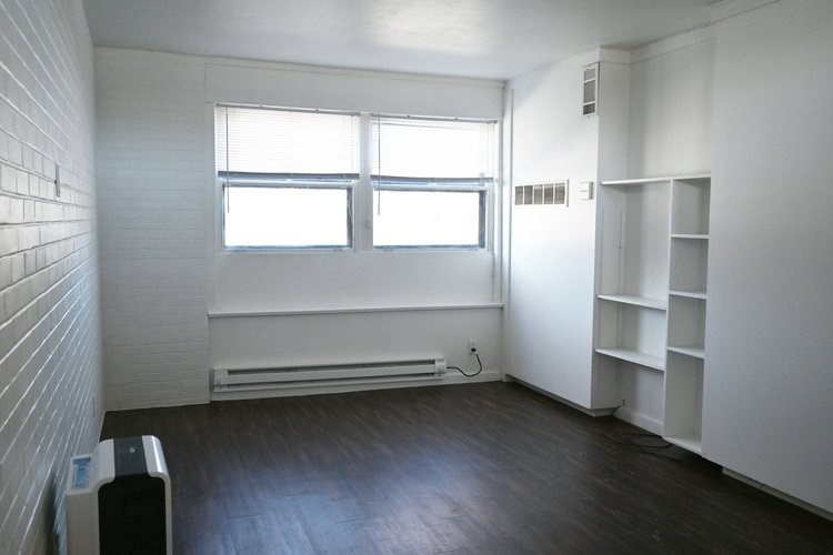 A room with a window, a radiator, and a shelf.