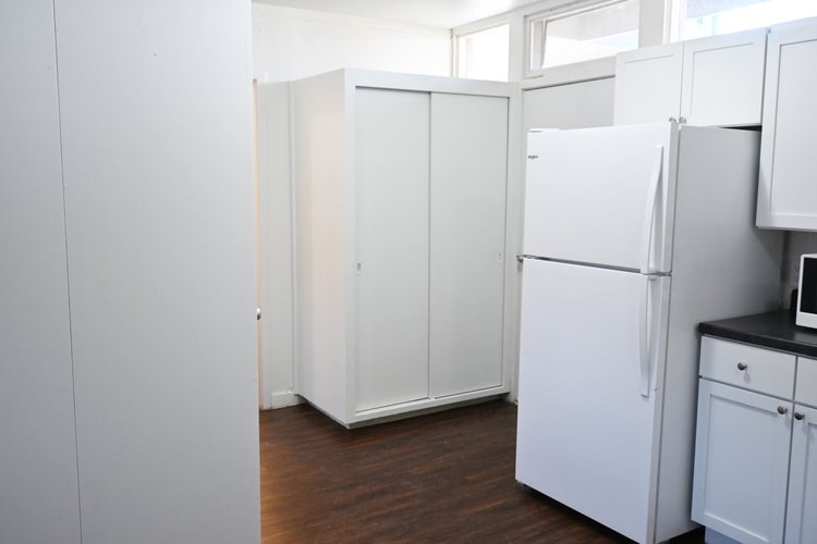 A kitchen with white appliances and cabinets.