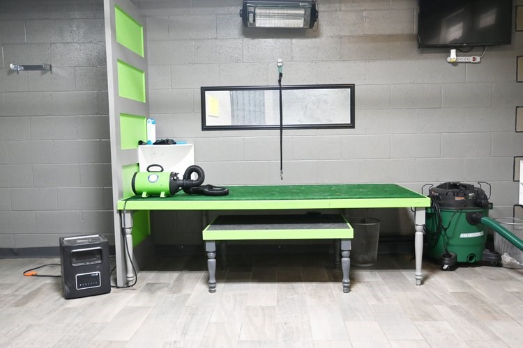 A room with a green table, a bench and a speaker.