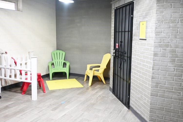 A room with a white crib, a green chair, a yellow chair, and a red stool.