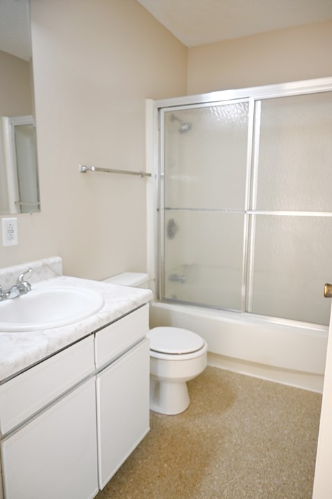 A white bathroom with a sink, toilet and shower.