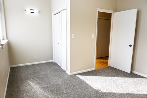 A room with a carpeted floor and two doors, one of which is open.
