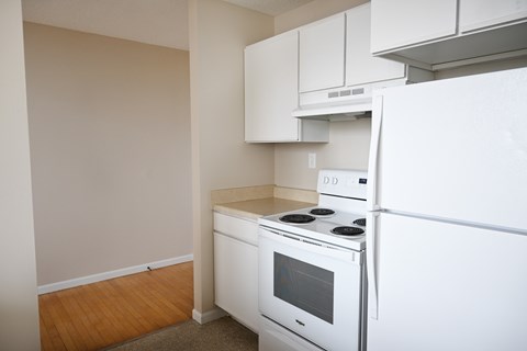 A white stove and refrigerator in a kitchen with white cabinets.