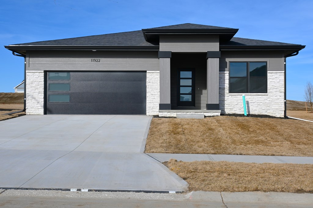 A modern house with a grey garage door and a black roof.