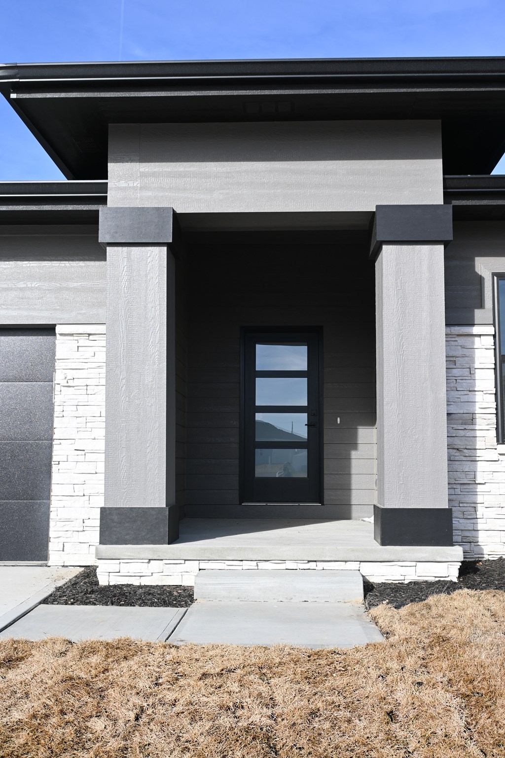 A modern house with a grey front and a glass door.