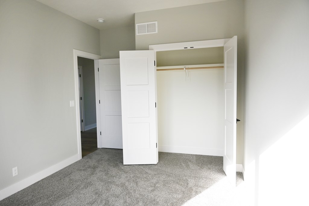 A room with a white closet and carpeted floor.