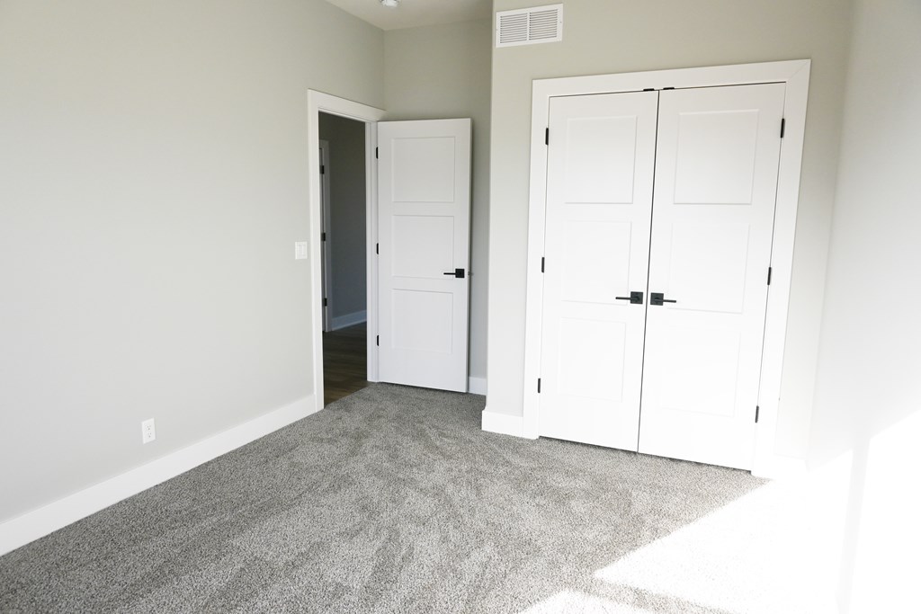 A room with a carpeted floor and two white doors.