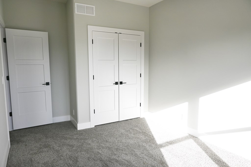 A room with two white doors and a carpeted floor.