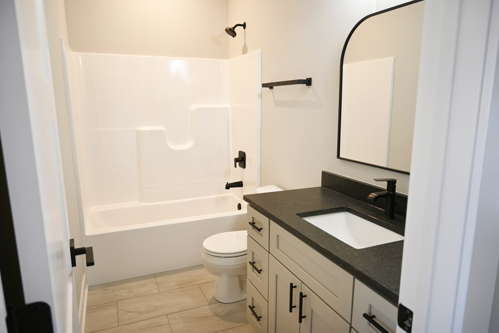 A white toilet sits in a bathroom next to a sink.