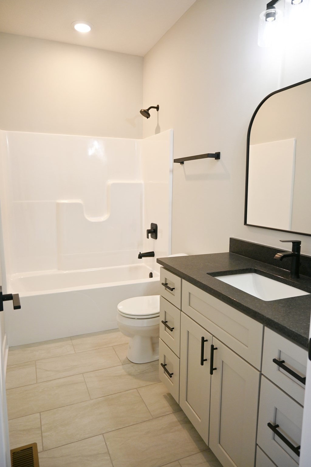 A white toilet sits in a bathroom with a black counter top.