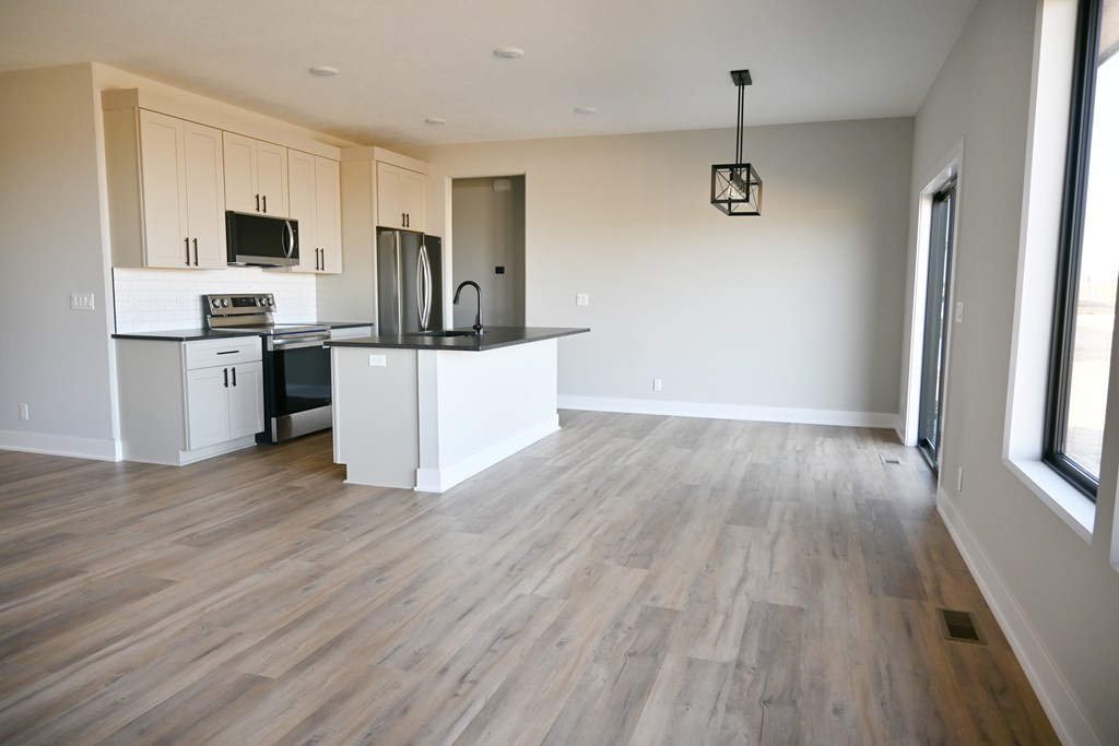 A kitchen with a white countertop and wooden flooring.