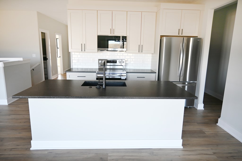 A kitchen with a black countertop and stainless steel appliances.