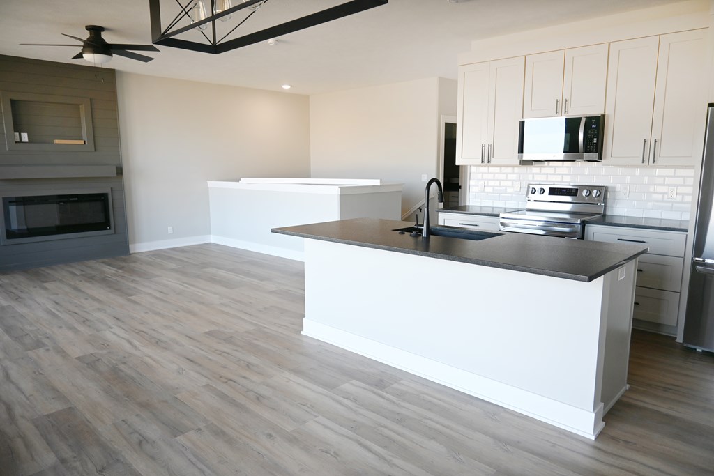A modern kitchen with a large island and a ceiling fan.