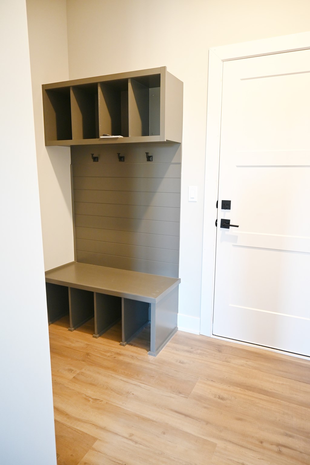 A white door is next to a shelf with several compartments.