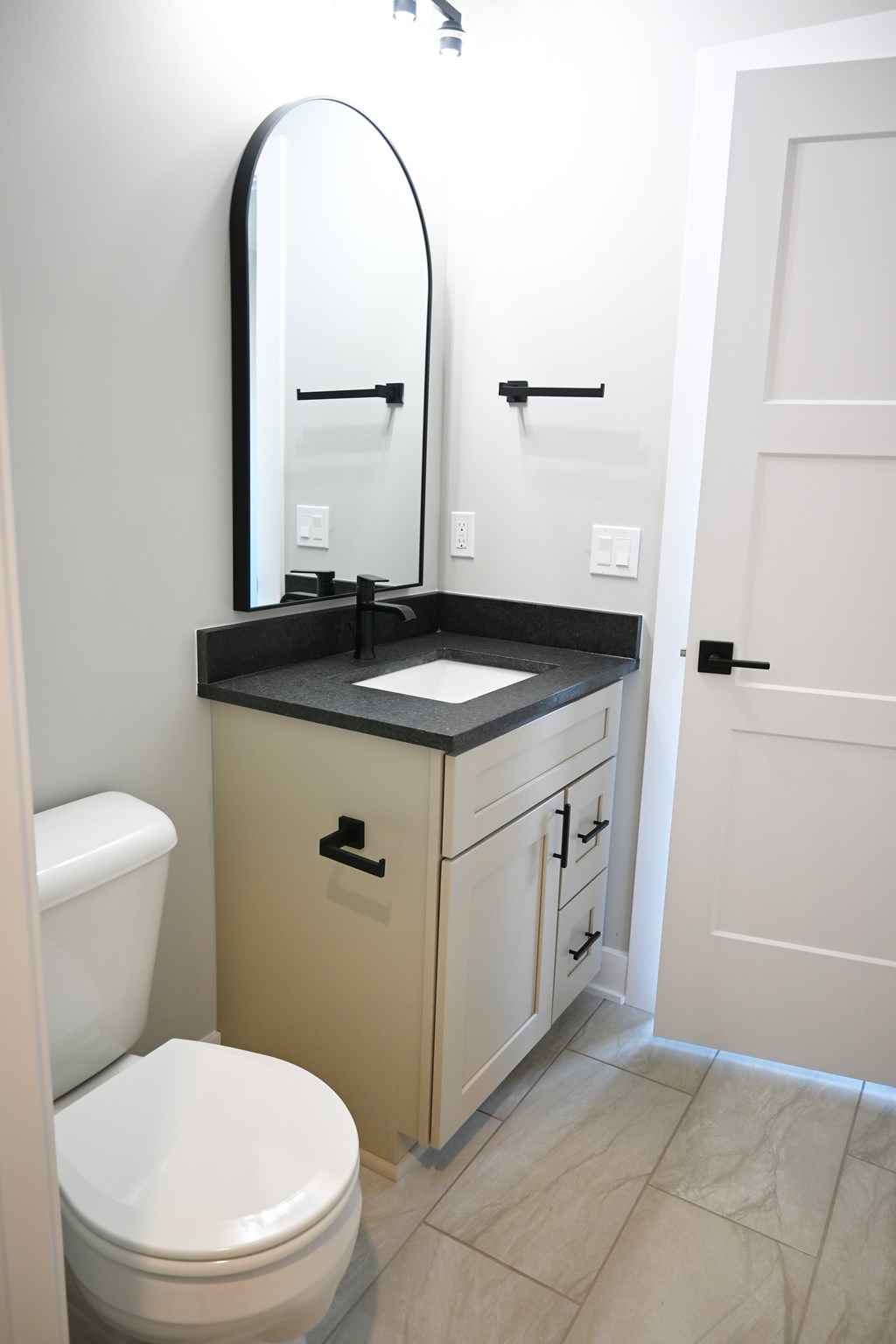 A bathroom with a toilet, sink, and mirror.