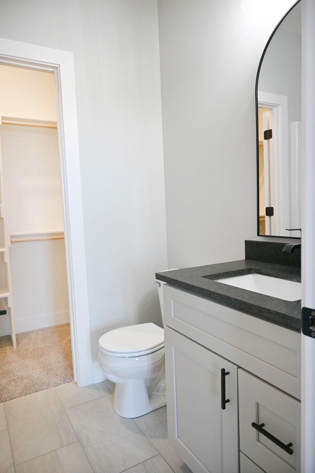 A white toilet sits in a bathroom next to a sink.