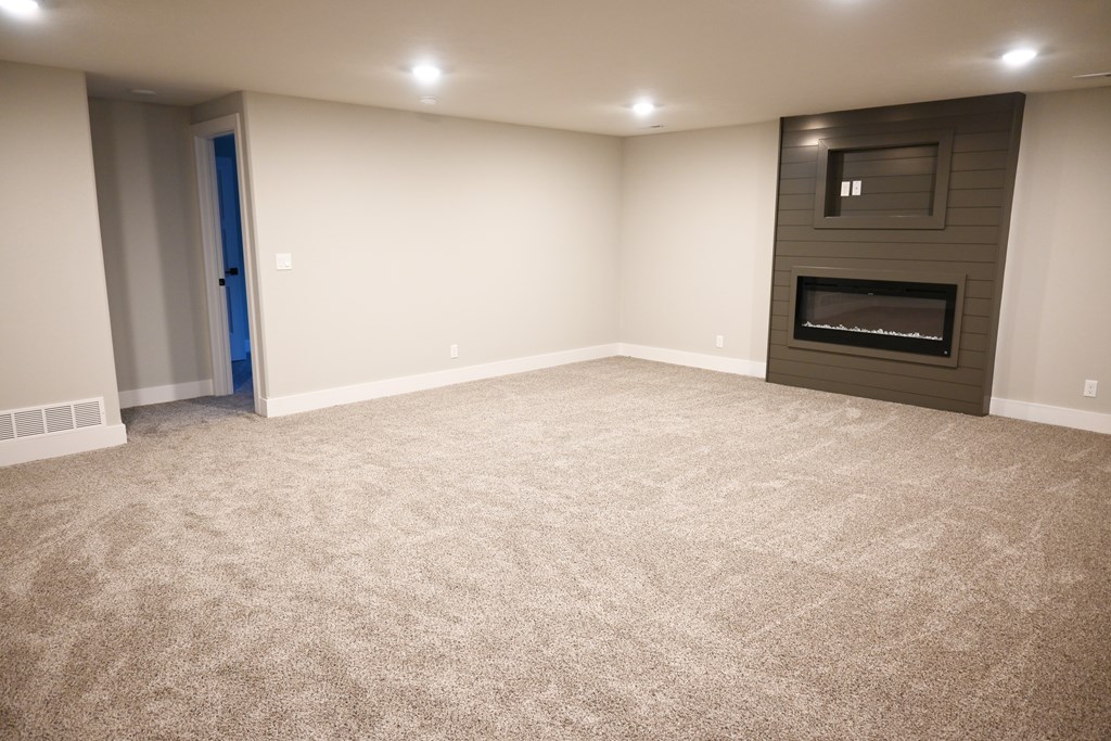 A room with a carpeted floor and a fireplace.