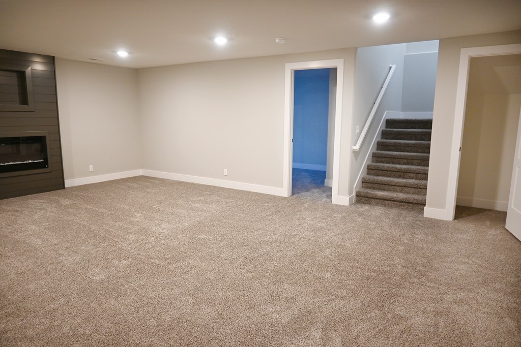 A room with a carpeted floor and a staircase.