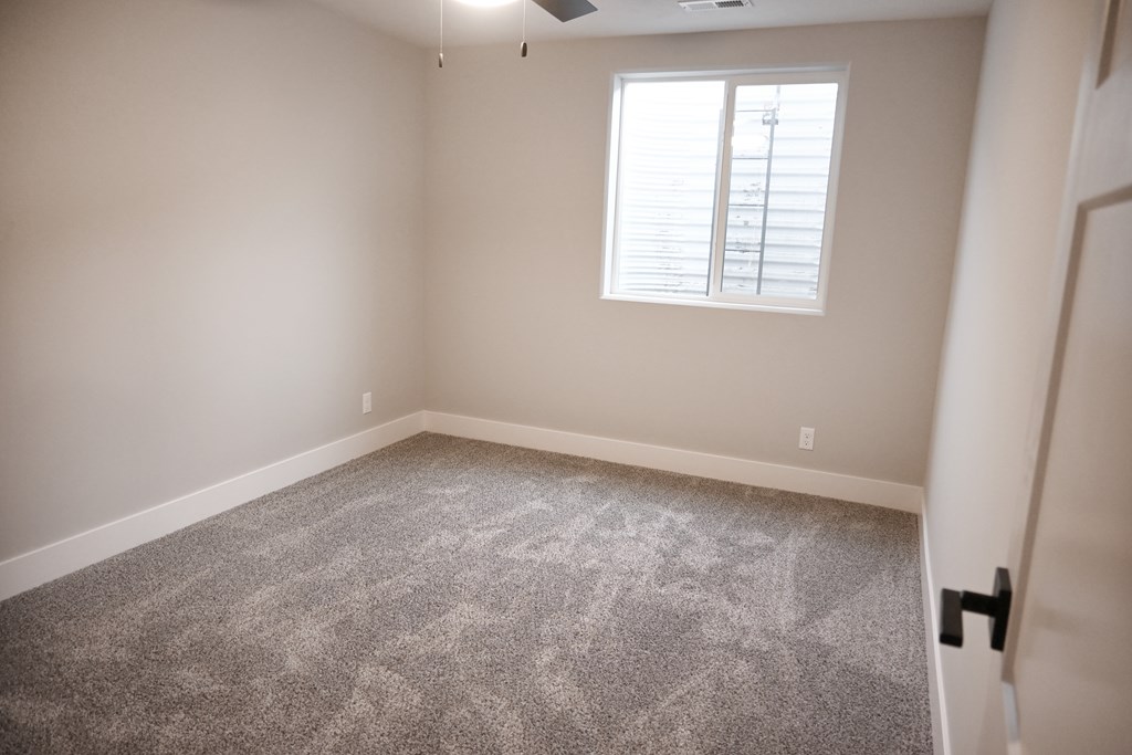 A room with a carpeted floor and a window with blinds.