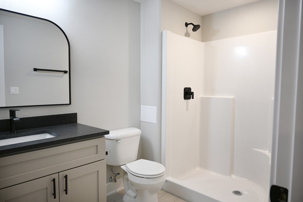 A white toilet sits in a bathroom next to a sink and a shower.