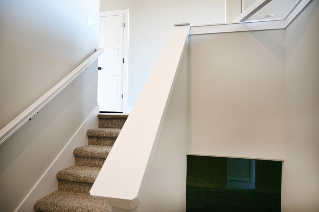 A staircase with a carpeted runner and white handrail.