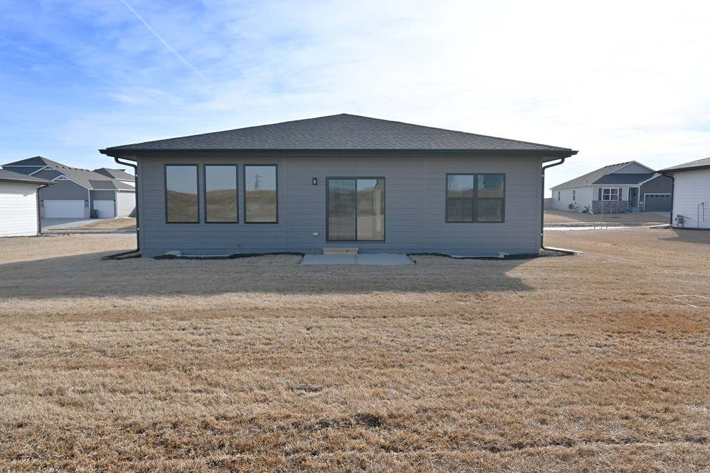 A grey house with a brown lawn in front of it.