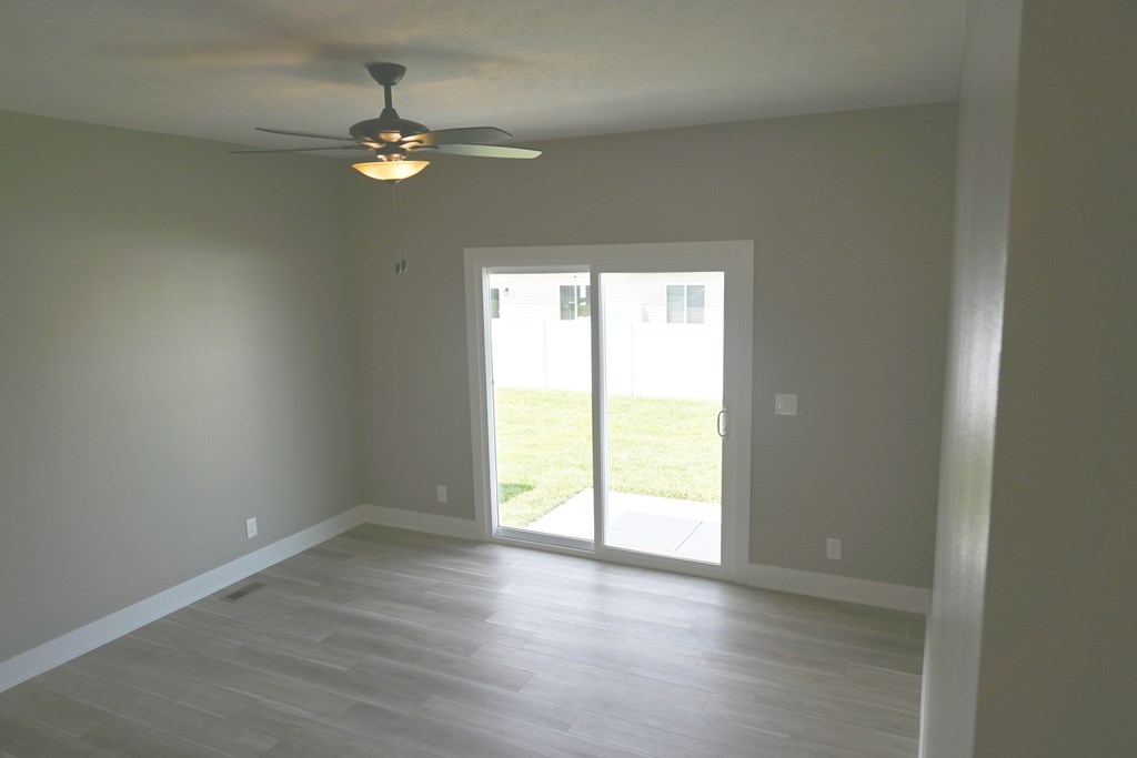 A room with a ceiling fan and sliding glass doors.