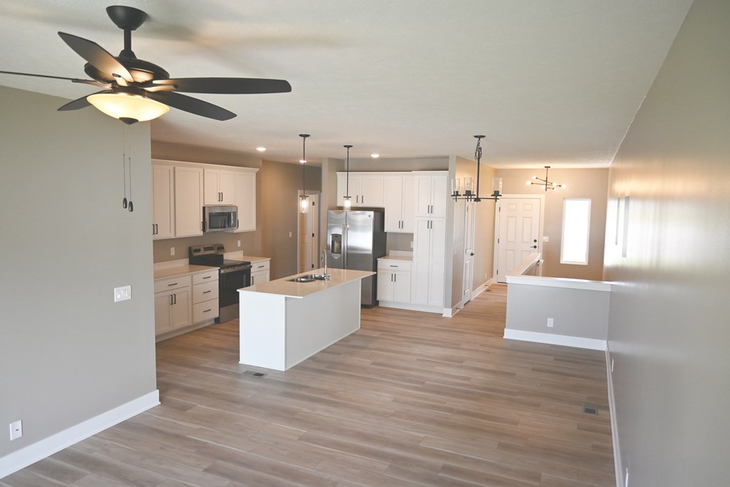 A kitchen with a fan on the ceiling and wooden floors.