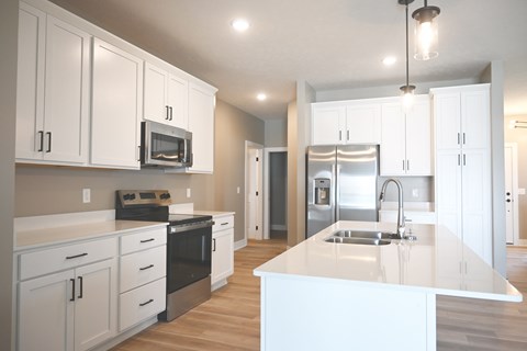 A kitchen with white cabinets and a white island.