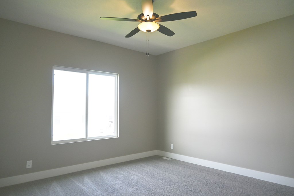 A room with a ceiling fan and a window.